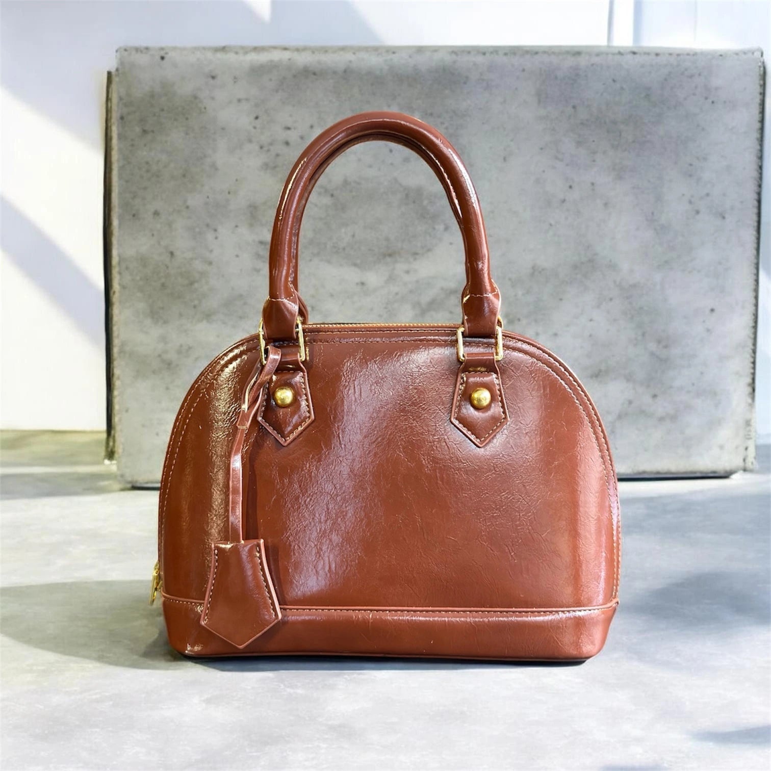 Cartera elegante de mano en material ecocuero con detalle colgante