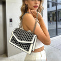 Cartera de hombro estructurada color blanco con solapa de textura animal print y correa de cadena dorada.