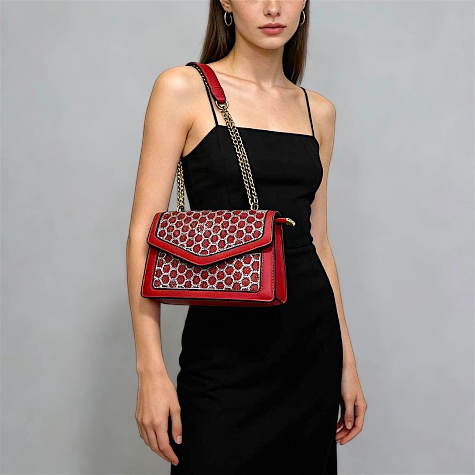 Cartera de hombro estructurada color rojo con solapa de textura animal print y correa de cadena dorada.