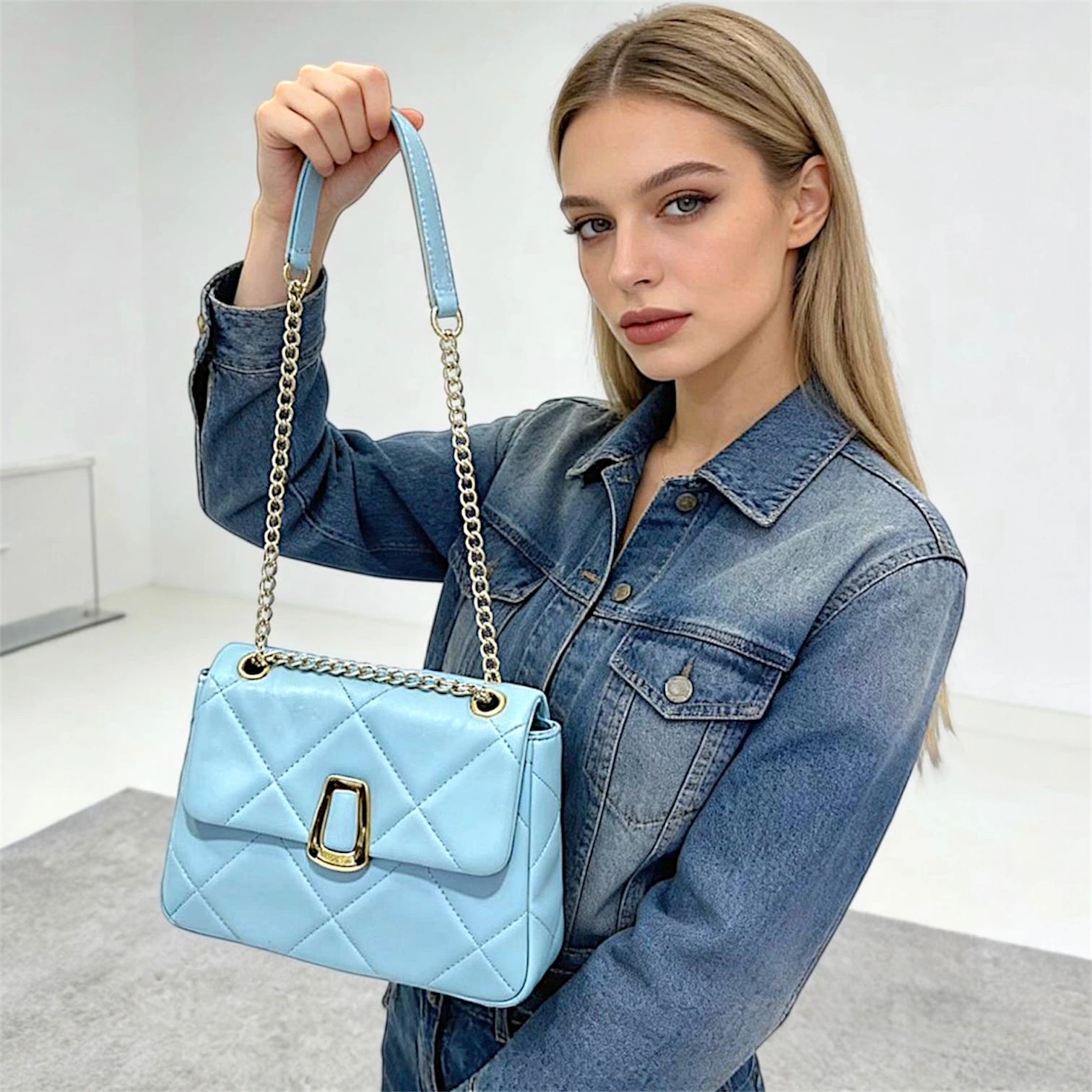 Cartera de hombro estructurada con diseño acolchado de rombos de gran tamaño (maxi quilting). Incluye una solapa frontal con cierre metálico dorado de diseño único y una correa de cadena dorada entrelazada que pasa por ojales metálicos superiores. 