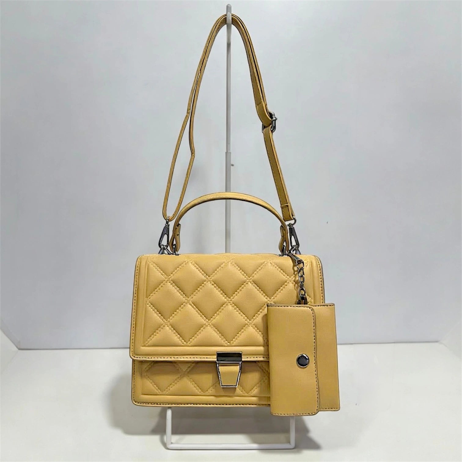 Bolso de mano con textura acolchada en patrón de diamantes y broche metálico plateado en color amarillo