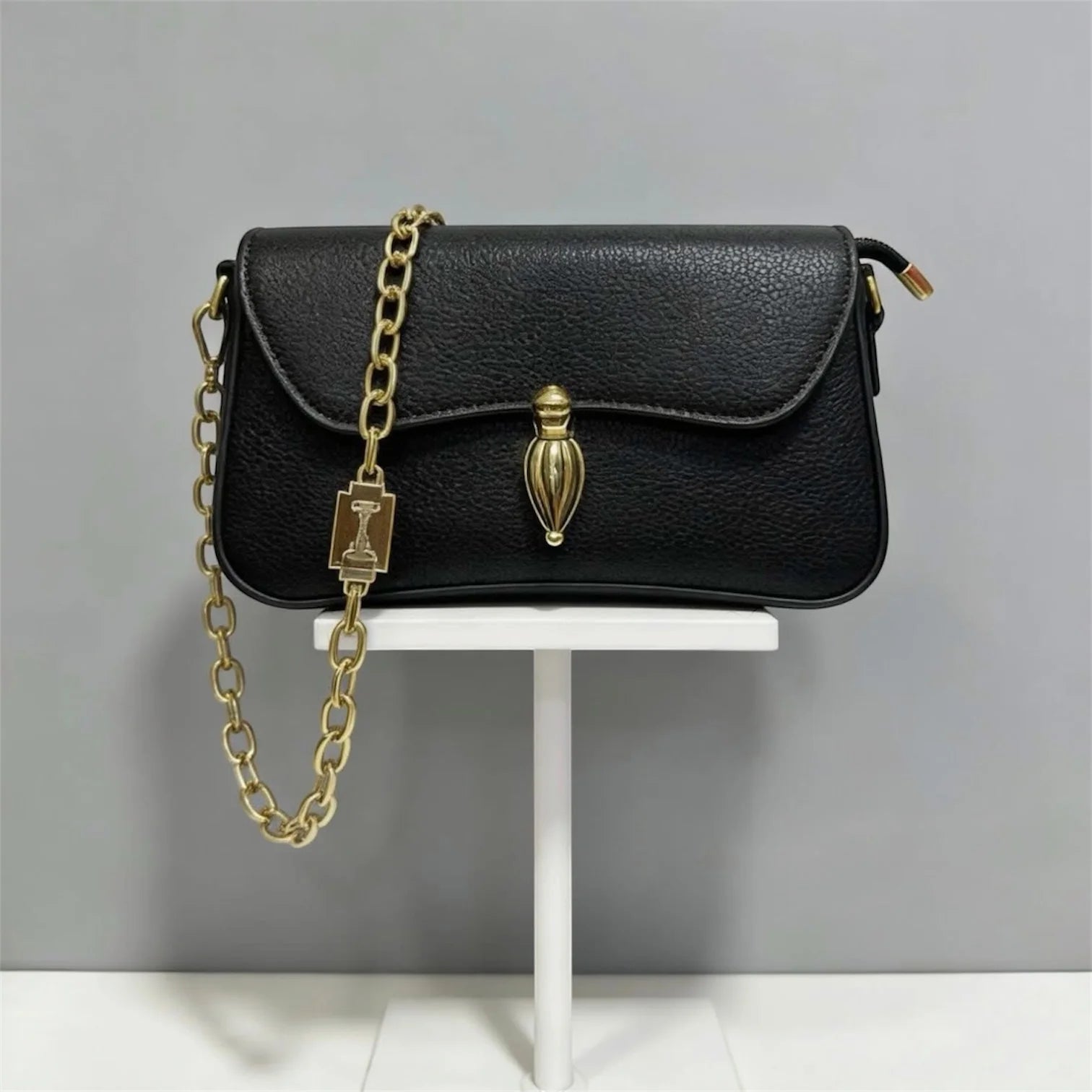 Bolso bandolera de gamuza en tono verde pálido con broche dorado ovalado distintivo y correa de cadena, estilo sofisticado y minimalista.