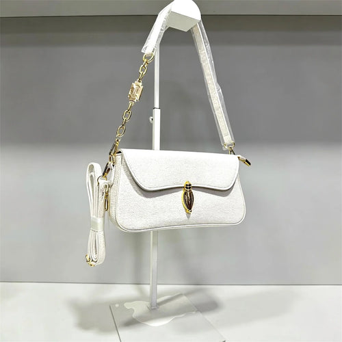 Bolso bandolera de gamuza en tono verde pálido con broche dorado ovalado distintivo y correa de cadena, estilo sofisticado y minimalista.