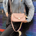 Cartera crossbody con diseño minimalista y herrajes dorados, perfecta para complementar un look casual