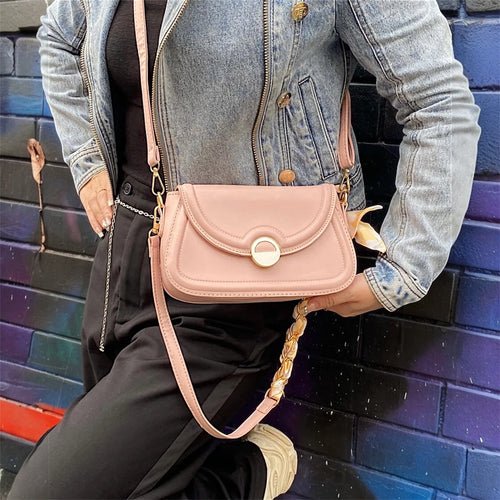 Cartera crossbody con diseño minimalista y herrajes dorados, perfecta para complementar un look casual