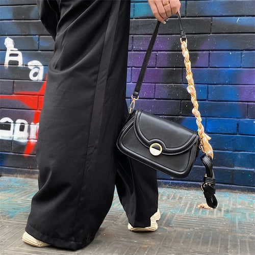 Cartera crossbody con diseño minimalista y herrajes dorados, perfecta para complementar un look casual