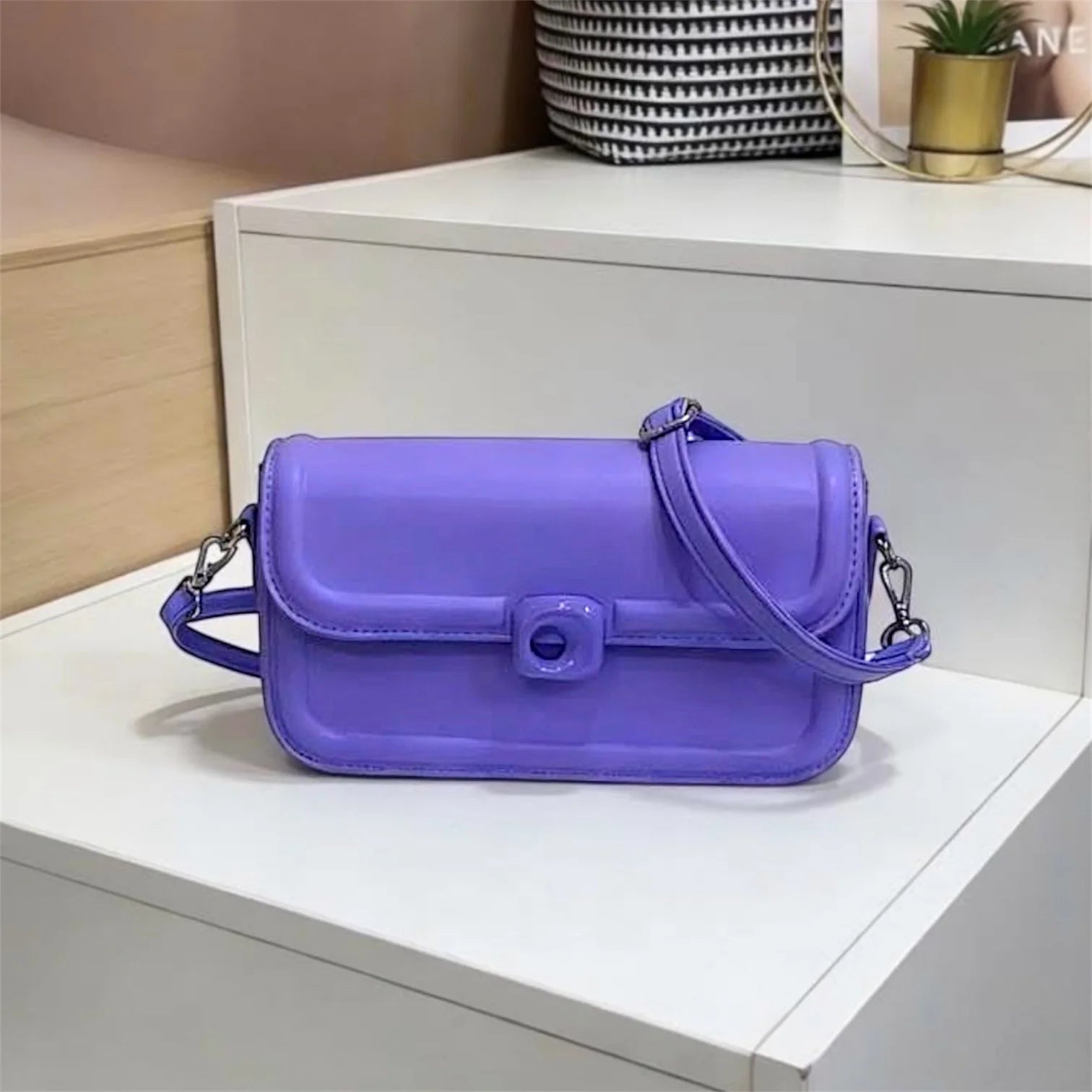 Bolso tipo bandolera de diseño minimalista con estructura redondeada y cierre circular central distintivo