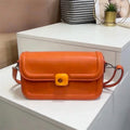 Bolso tipo bandolera de diseño minimalista con estructura redondeada y cierre circular central distintivo