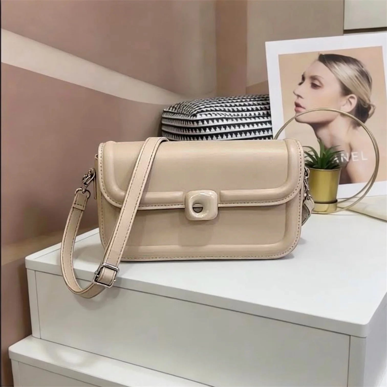Bolso tipo bandolera de diseño minimalista con estructura redondeada y cierre circular central distintivo