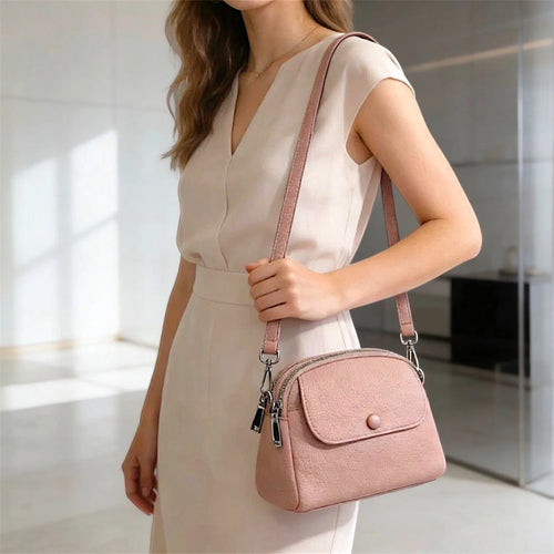 Bolso de hombro compacto con diseño estructurado, textura granulada, solapa frontal con botón decorativo y cierre de cremallera metálica